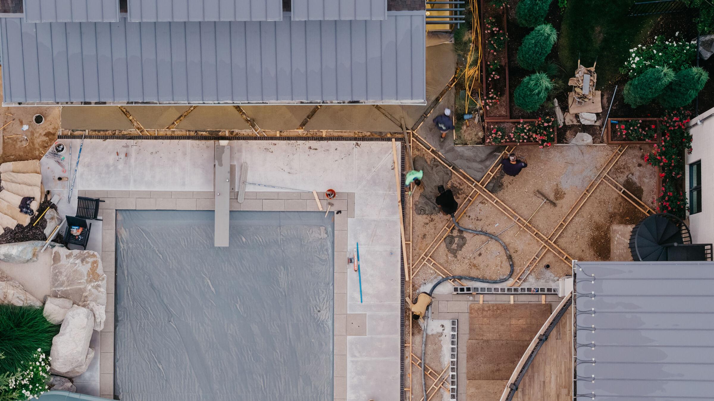 Overhead view of a back yard mid-build — slabs formed and poured before any surround is built
